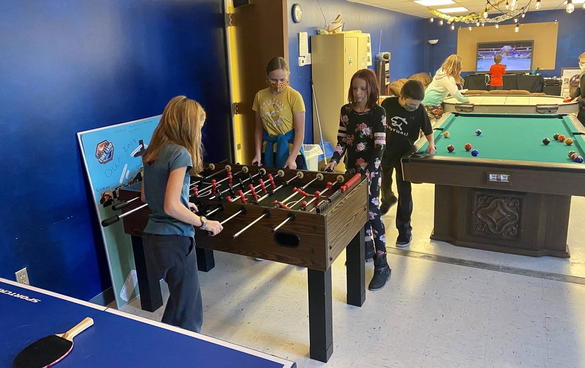 Children playing foosball and other table games in the KCMC game room
