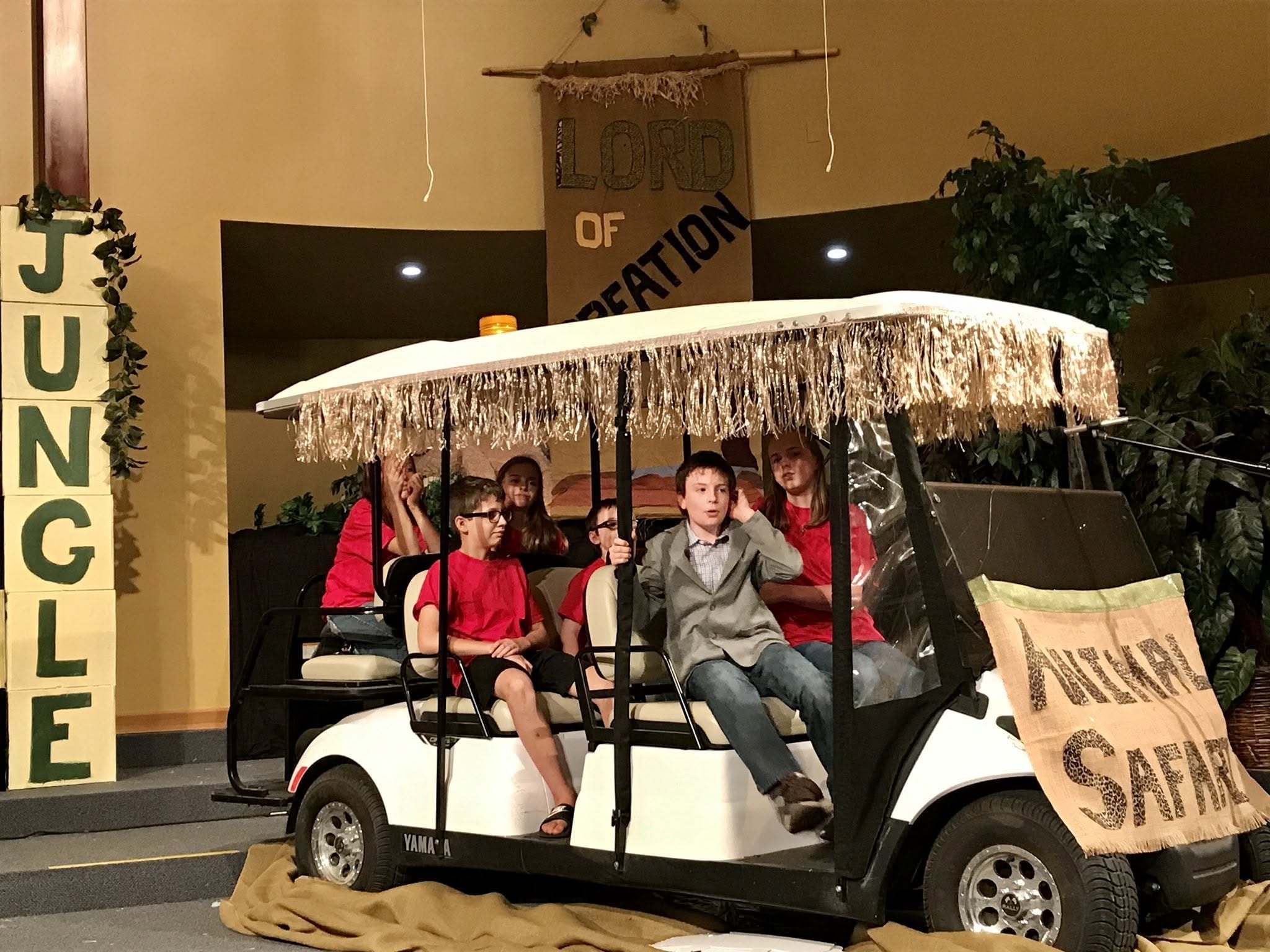 Children seated in a decorated safari cart inside KCMC